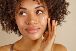 Smiling woman using skincare product on the cheek
