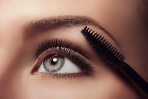 A cosmetologist beautifies a client’s eye