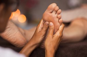 Therapist uses two hands for foot reflexology massage to balance chakras
