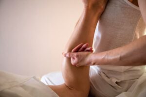 Massage therapist massaging client's calf muscle