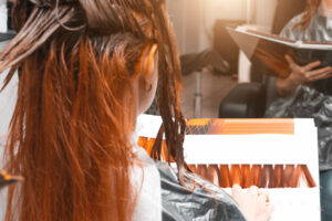 Client examines book of hair colors while receiving color melting hair treatment